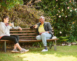 Two friends sitting on a bench, talking and laughing