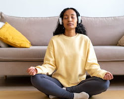 person sitting in a comfortable position, closing their eyes, and focusing on their breath